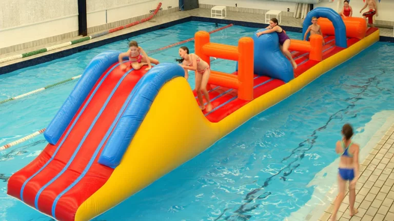 Kids playing on a large inflatable obstacle course, floating in a pool