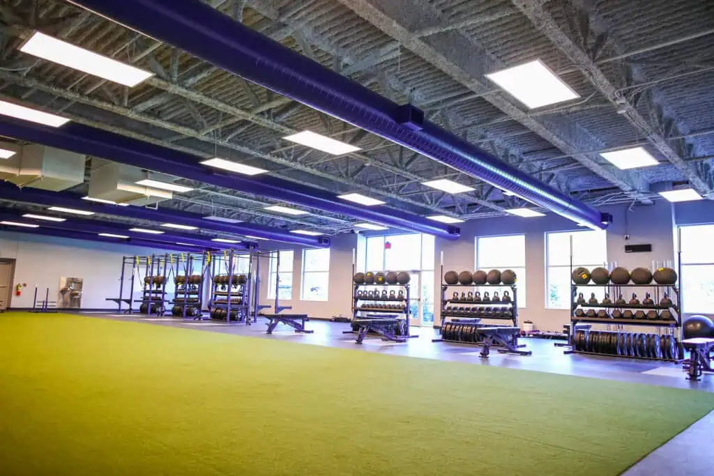 The TAC fitness center with turf area, weights, kettlebells, and natural light.