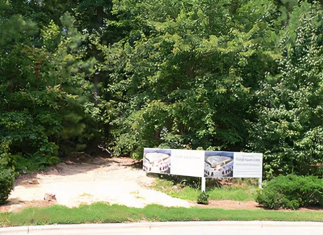 The sign advertising the construction of TAC on the newly purchased plot of land, think with trees